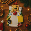 Load image into Gallery viewer, Decorative  teacher angel ornament with a teddy bear holding an apple on a wooden surface with Christmas decorations.

