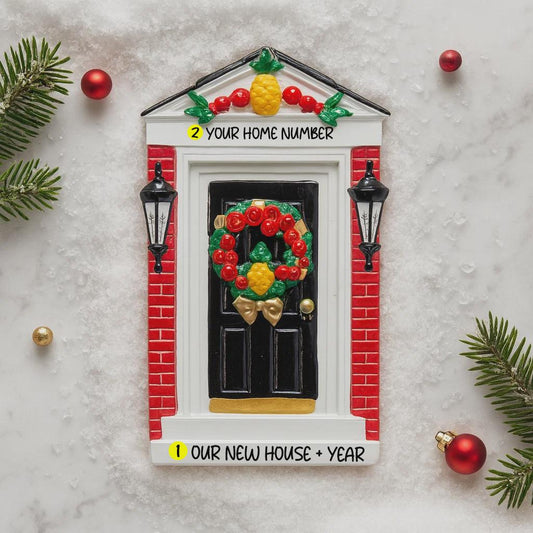 Decorative house-shaped ornament with a wreath, street lamps, and text on a marble surface.