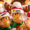 Load image into Gallery viewer, Close up view of a personalized reindeer couple ornament featuring two festive reindeer wearing Santa hats with customizable names. Designed to celebrate couples, families, siblings, or loved ones, this ornament highlights togetherness and holiday warmth. A charming Christmas keepsake perfect for tree decor, gift giving, and preserving shared holiday memories.

