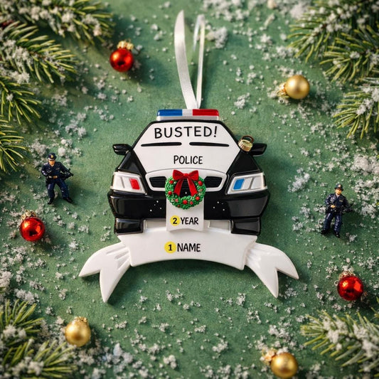 Personalized police car Christmas ornament featuring a black and white cop car design with BUSTED text, police lights and festive wreath detail. Customized with a name and year on the front banner. Glossy resin finish with bold black and white colors creates a fun and playful holiday look. Mostly 2D ornament with raised 3D details on the front only, lightweight and perfect for Christmas tree decor and police themed gifts.