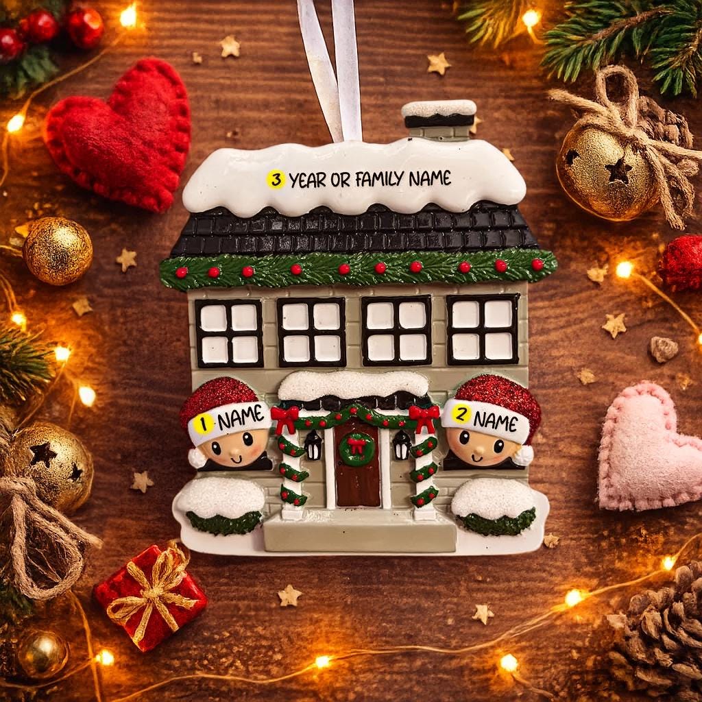 Personalized Christmas house ornament featuring a cozy winter home decorated with snow, wreaths, garlands, and festive details. Two smiling characters wearing Santa hats peek from the front, each customizable with a name, while the roof displays a year or family name. Designed with a detailed 3D raised front and smooth finish, this ornament is perfect for Christmas tree decor, family keepsakes, new home celebrations, and holiday gifting.
