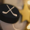 Load image into Gallery viewer, Close-up of a hockey puck with crossed sticks on a blurred background
