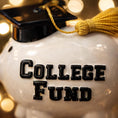 Load image into Gallery viewer, White piggy bank with 'College Fund' text and graduation cap, blurred lights in the background
