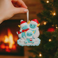 Load image into Gallery viewer, Decorative Christmas ornament of a family of three with a blurred Christmas tree and fireplace in the background.
