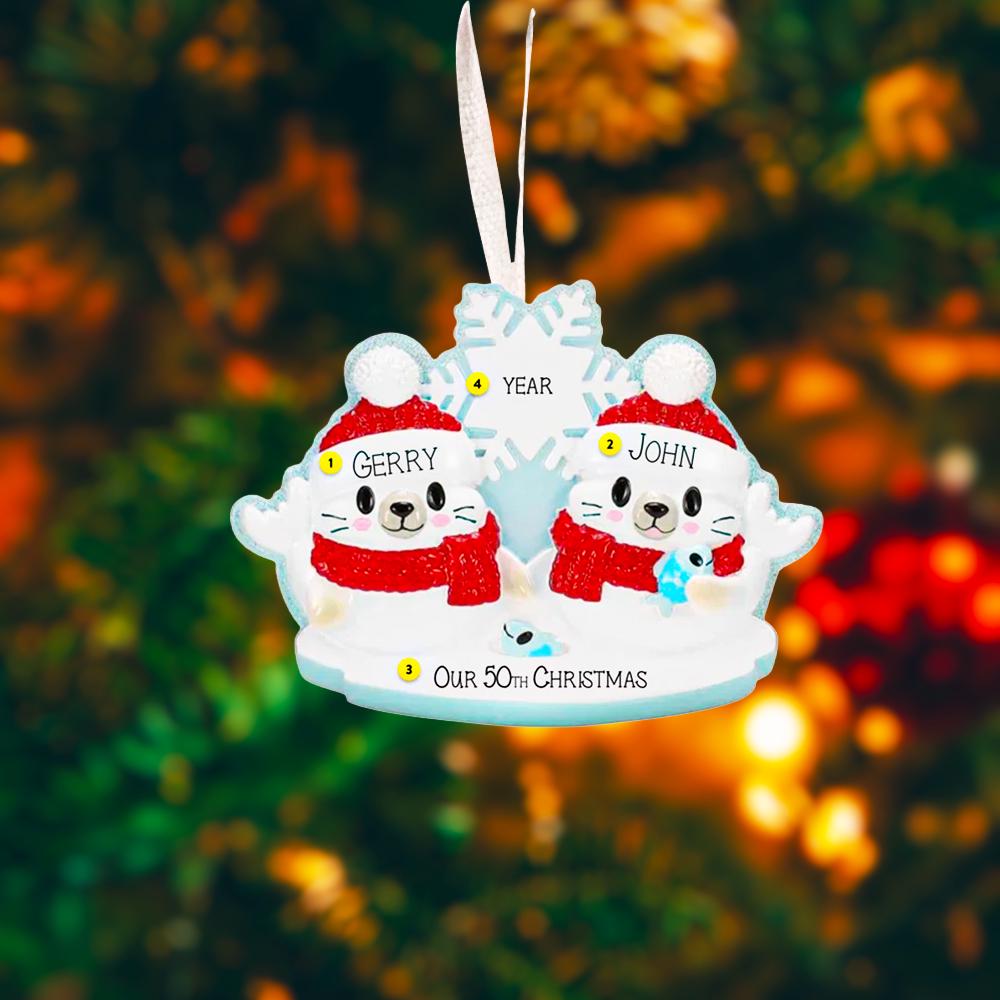 Personalized Christmas ornament with two characters wearing Santa hats and scarves against a blurred festive background.