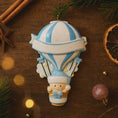 Load image into Gallery viewer, Personalized Baby Boy First Christmas Ornament designed as a charming 3D hot air balloon with a sweet baby in the basket below. The name is featured on the lower section and the year or Baby’s First Christmas message appears on the banner across the balloon. Soft blue and white tones, glitter accents, and raised dimensional details create a playful keepsake. Perfect for newborn boys, baby shower gifts, and celebrating a baby’s first holiday season.
