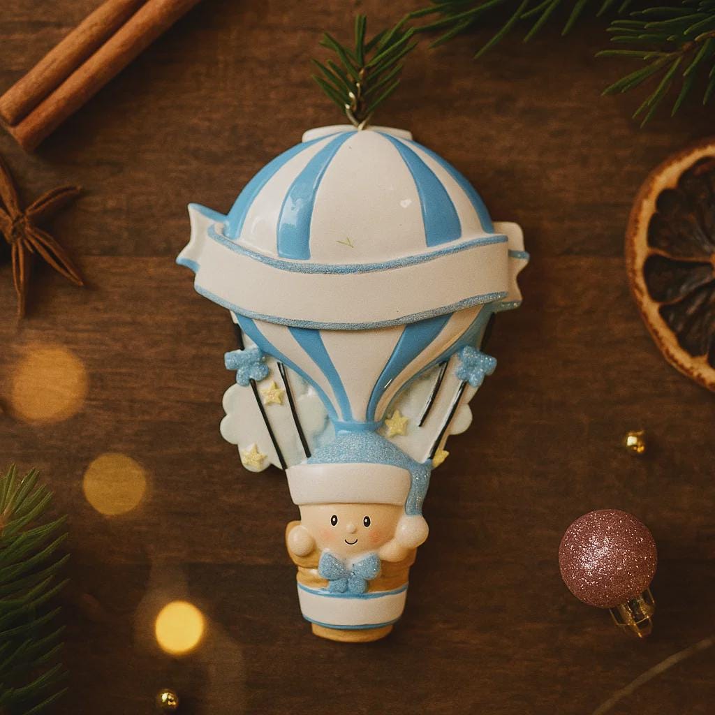 Personalized Baby Boy First Christmas Ornament designed as a charming 3D hot air balloon with a sweet baby in the basket below. The name is featured on the lower section and the year or Baby’s First Christmas message appears on the banner across the balloon. Soft blue and white tones, glitter accents, and raised dimensional details create a playful keepsake. Perfect for newborn boys, baby shower gifts, and celebrating a baby’s first holiday season.