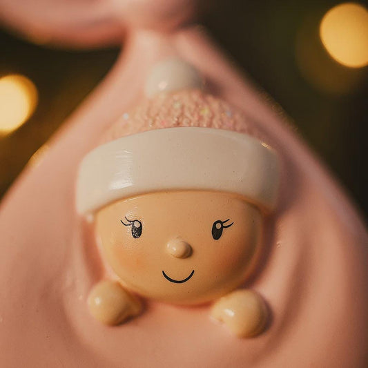 Decorative item shaped like a baby with a smiling face, held in a mouth.