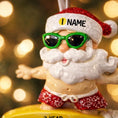 Load image into Gallery viewer, Personalized surfing Santa Christmas ornament featuring a fun beach themed Santa riding a wave on a surfboard. Raised 3D front details add depth while the back remains flat for easy hanging. Custom name and year placement make this ornament a playful and unique holiday keepsake for Christmas tree decor.
