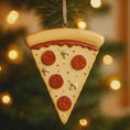 Load image into Gallery viewer, Pizza slice ornament hanging on a Christmas tree with blurred lights in the background
