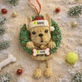 Load image into Gallery viewer, Dog-shaped Christmas ornament with customizable name and age tag on a sandy background with Christmas decorations.
