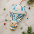 Load image into Gallery viewer, Personalized Baby Boy First Christmas Ornament designed as a charming 3D hot air balloon with a sweet baby in the basket below. The name is featured on the lower section and the year or Baby’s First Christmas message appears on the banner across the balloon. Soft blue and white tones, glitter accents, and raised dimensional details create a playful keepsake. Perfect for newborn boys, baby shower gifts, and celebrating a baby’s first holiday season.

