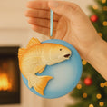 Load image into Gallery viewer, Hand holding a fish-shaped Christmas ornament with a fireplace and tree in the background
