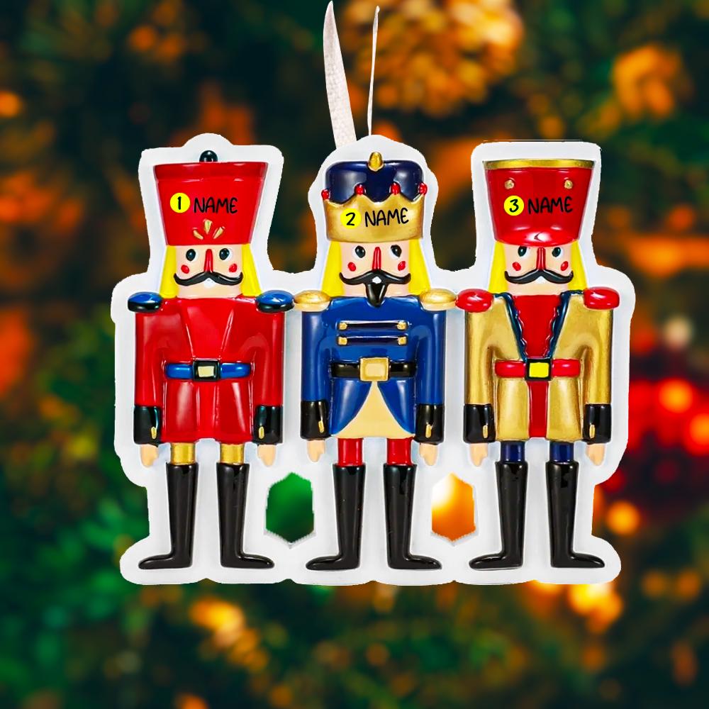 Three colorful nutcracker figurines with customizable names against a blurred Christmas tree background.