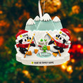 Load image into Gallery viewer, Decorative ornament with penguins fishing, personalized with names and year, against a blurred festive background.

