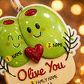 Load image into Gallery viewer, Decorative ornament with two green olives holding a red heart, text 'Olive You', and customizable names on a blurred light background.
