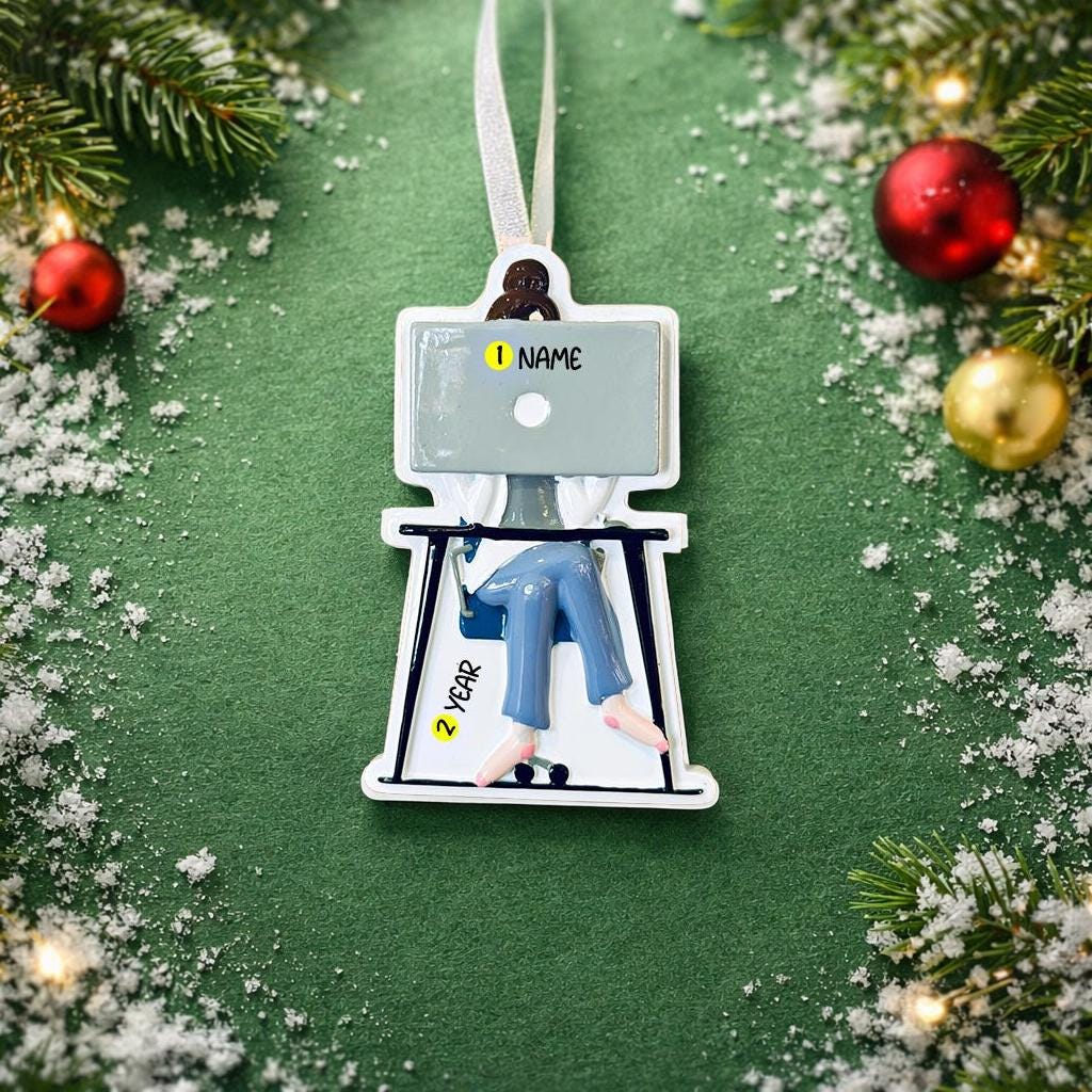 Decorative ornament with a person on a laptop, surrounded by Christmas decorations.