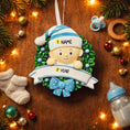 Load image into Gallery viewer, Personalized Baby Boy Christmas Ornament featuring a sweet child peeking from a festive green wreath with blue accents and polka dot bow. This ornament has a raised 3D front design with detailed holly leaves, textured elements, and dimensional lettering. The name is placed on the hat and the year on the banner. A meaningful keepsake for baby’s first Christmas, newborn gift, or holiday memory decoration for the Christmas tree.
