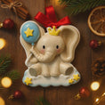 Load image into Gallery viewer, Decorative elephant ornament with a blue balloon and red bow on a wooden surface with Christmas decorations.
