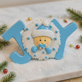 Load image into Gallery viewer, Decorative letter 'JOY' with a baby face design on a snowy background with Christmas decorations.
