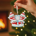 Load image into Gallery viewer, Decorative Christmas ornament with snowmen in red hats and scarves held by a hand against a festive background.
