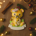 Load image into Gallery viewer, Personalized baby lion Christmas ornament featuring a sweet yellow lion cub wearing a floral crown and holding a small leaf. The bottom banner can be customized with name and year, creating a unique keepsake for a newborn or toddler. Designed in warm yellow and soft pastel tones, this resin baby Christmas ornament is perfect for celebrating Baby’s First Christmas or adding a personalized jungle themed touch to your holiday tree.
