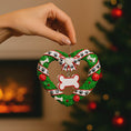 Load image into Gallery viewer, Heart-shaped Christmas ornament with paw prints and bones, held by a hand against a festive background.
