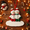 Load image into Gallery viewer, Two snowman ornaments on a wooden surface with Christmas decorations.
