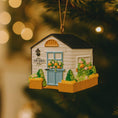 Load image into Gallery viewer, Decorative ornament of a shed with plants on a blurred Christmas tree background
