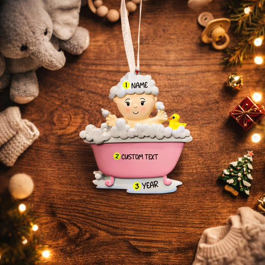 Personalized Christmas ornament of a baby in a bath with customizable text on a wooden surface.