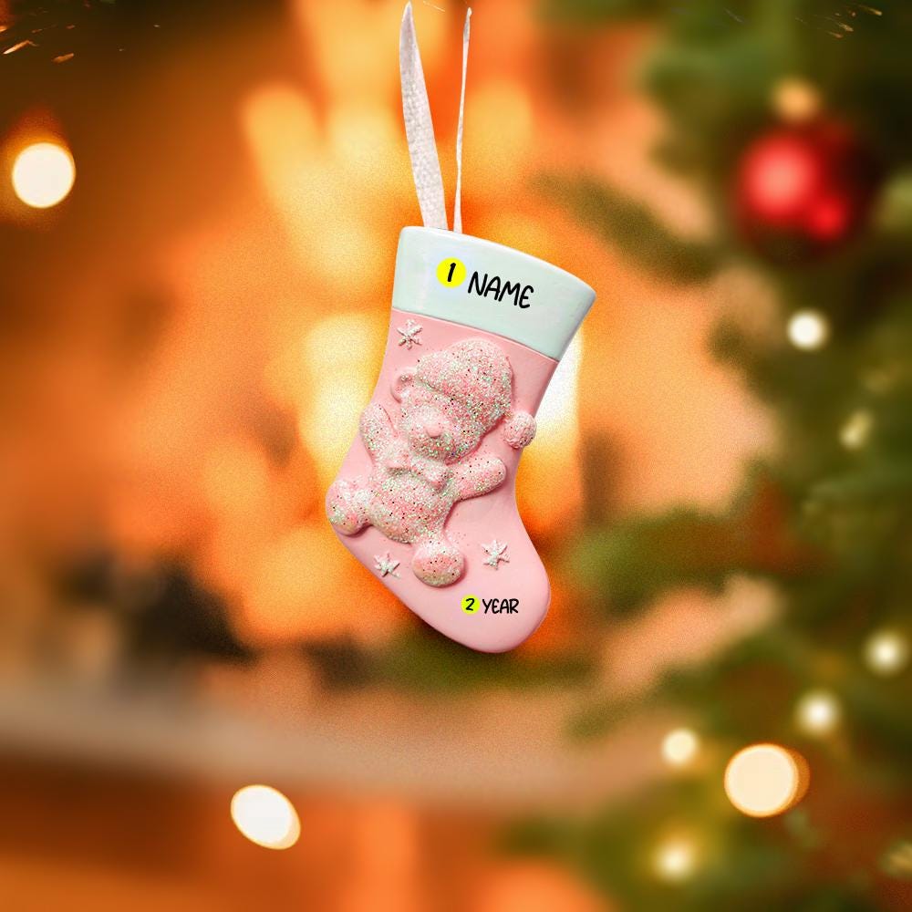 Pink teddy bear-themed ornament ornament with 'NAME' and '2 YEAR' text, Christmas tree background.