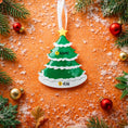 Load image into Gallery viewer, Christmas tree-shaped ornament with customizable text on a decorative background with ornaments and snow.
