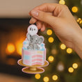 Load image into Gallery viewer, Personalized gender reveal Christmas ornament for baby girl featuring a pastel cake design with a cute elephant topper and its a gender message, soft pink and blue tones with layered cake details and glossy finish, styled as a sweet holiday keepsake for expecting parents, baby announcement and first Christmas memories, displayed on a warm wooden background with cozy Christmas lights, baby shoes and festive decor creating a joyful and heartwarming celebration scene
