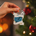 Load image into Gallery viewer, A cozy knitting yarn ornament featuring a detailed blue ball of yarn wrapped with flowing ribbon and raised knitting needles. The ornament has a sculpted 3D front with realistic yarn texture and smooth glossy finish, while the back is flat and 2D for easy hanging. Personalized with a handwritten name and year, this resin ornament is displayed in a warm festive setting with soft holiday lights, creating a heartfelt and nostalgic feel. Perfect for grandmother gifts, knitting lovers, and handmade craft themed 
