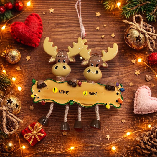 Decorative moose ornament with name tags on a wooden surface with Christmas decorations.