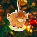 Load image into Gallery viewer, Adorable Highland cow themed Christmas ornament featuring a fluffy brown cow design with soft rounded details and a warm countryside feel. Styled in a natural green meadow setting, this ornament is designed to be personalized and brings a cozy farm inspired charm to holiday tree decor.

