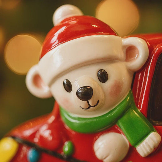 Decorative bear figurine wearing a Santa hat and green scarf against a blurred background
