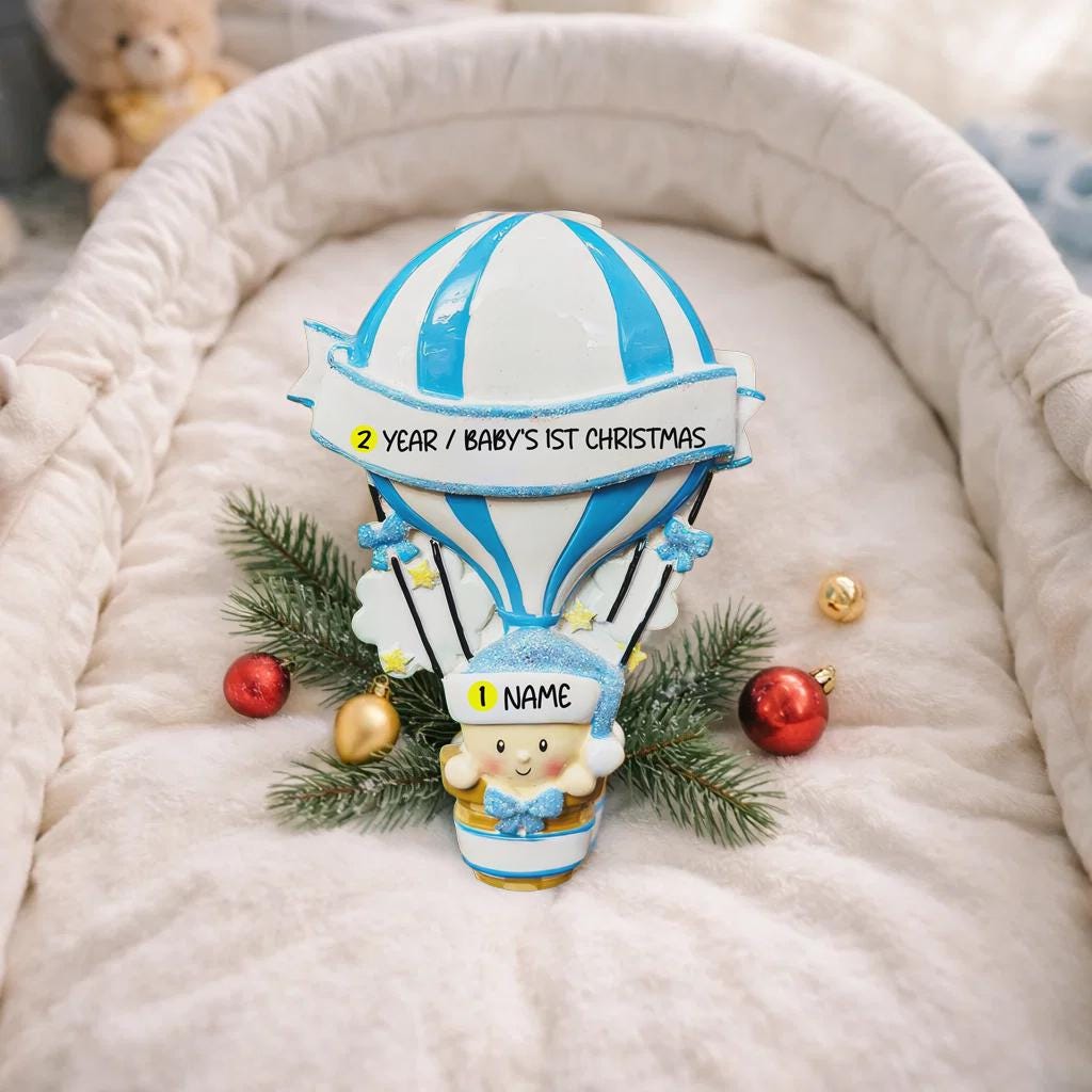 Personalized Baby Boy First Christmas Ornament designed as a charming 3D hot air balloon with a sweet baby in the basket below. The name is featured on the lower section and the year or Baby’s First Christmas message appears on the banner across the balloon. Soft blue and white tones, glitter accents, and raised dimensional details create a playful keepsake. Perfect for newborn boys, baby shower gifts, and celebrating a baby’s first holiday season.