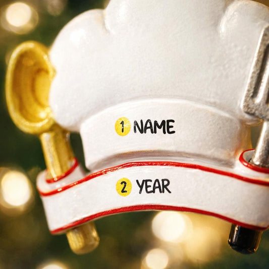 Personalized chef Christmas ornament featuring a white chef hat design with a wooden spoon and metal spatula details. Customized with a name and year on the front banner. Glossy resin finish with clean white and red accents creates a fun and professional cooking themed holiday look. Mostly 2D ornament with raised 3D details on the front only, lightweight and perfect for Christmas tree decor or kitchen themed gifts.