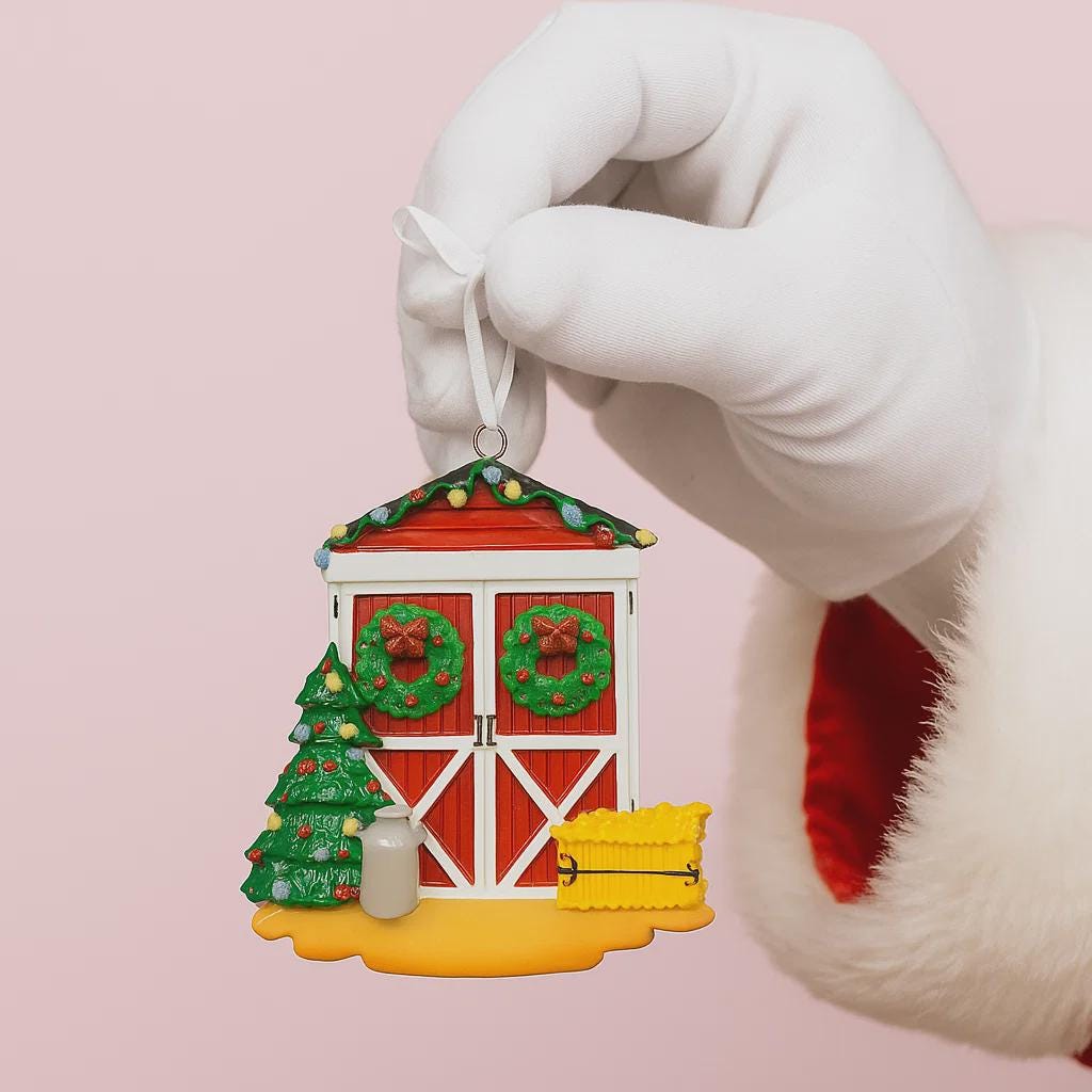 Hand wearing a white glove holding a Christmas-themed ornament on a pink background