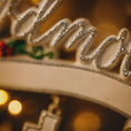 Load image into Gallery viewer, Decorative Christmas ornament with 'Mistletoe' text and blurred lights in the background

