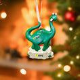Load image into Gallery viewer, Green dinosaur ornament with customizable text on a blurred Christmas tree background
