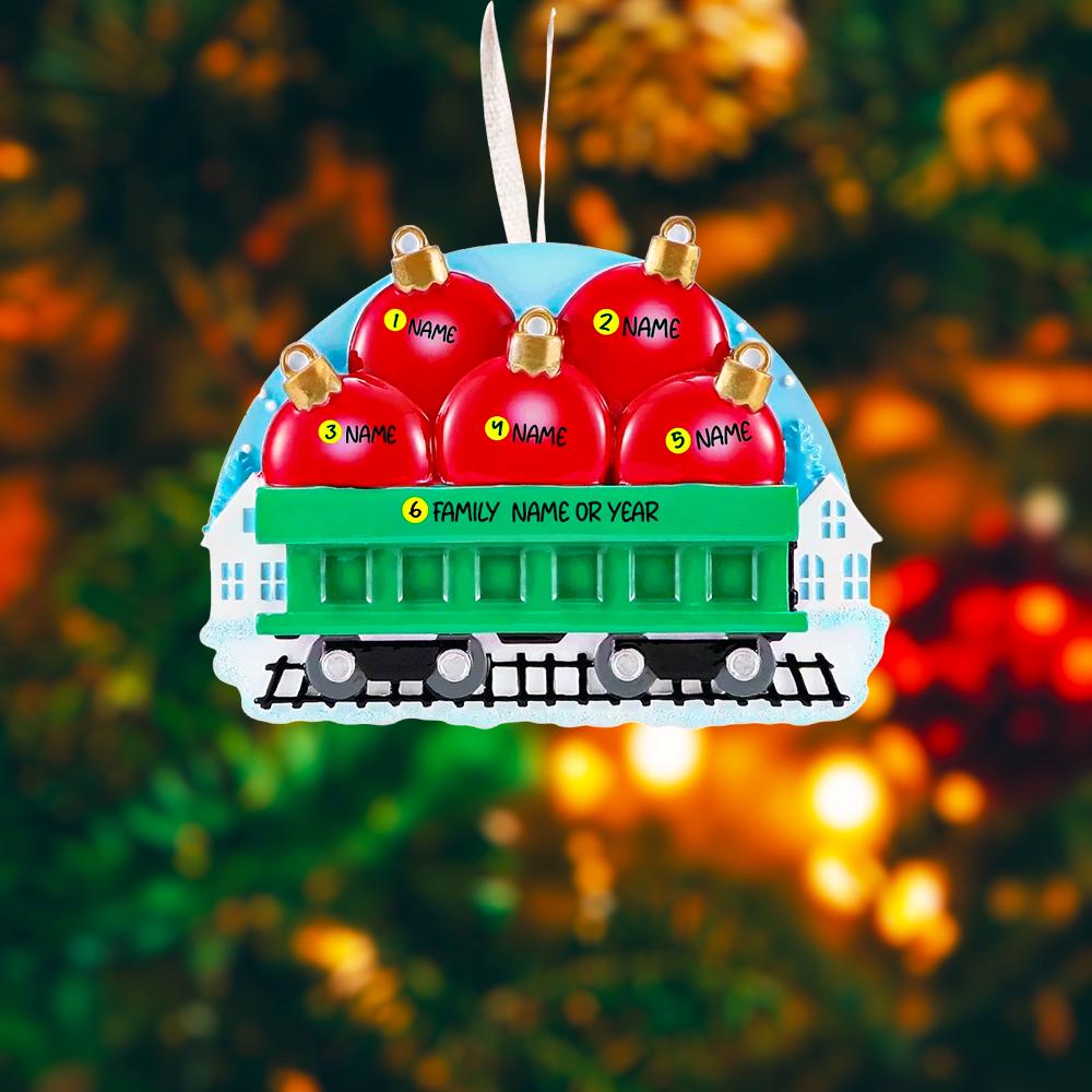 Christmas ornament shaped like a train with red carriages on a blurred Christmas tree background.