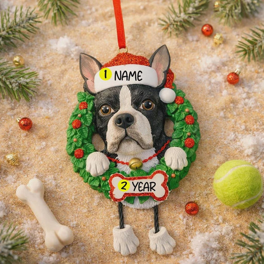Dog ornament with customizable name and year, surrounded by Christmas decorations on a sandy background.