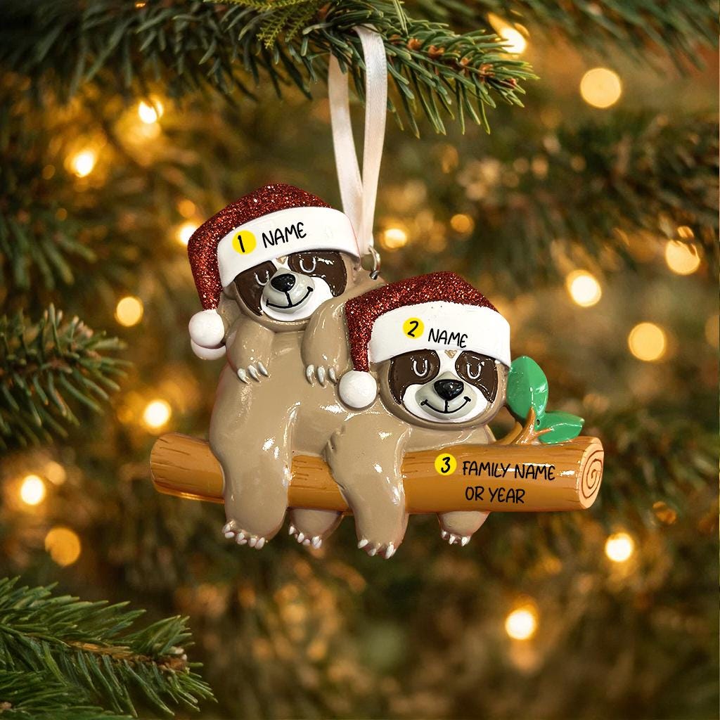 Two sloth ornaments on a log with name tags against a Christmas tree background