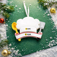 Load image into Gallery viewer, Personalized chef Christmas ornament featuring a white chef hat design with a wooden spoon and metal spatula details. Customized with a name and year on the front banner. Glossy resin finish with clean white and red accents creates a fun and professional cooking themed holiday look. Mostly 2D ornament with raised 3D details on the front only, lightweight and perfect for Christmas tree decor or kitchen themed gifts.
