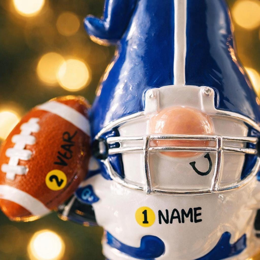 Personalized football gnome Christmas ornament featuring a blue and white gnome character wearing a football helmet and holding a football, customizable name area on the front body and customizable year area on the football, glossy finish with raised 3D front details and flat 2D back, white hanging ribbon, displayed on a snowy football field themed holiday background with pine branches and festive decorations.