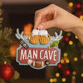 Load image into Gallery viewer, Man cave themed personalized ornament featuring a bold red Man Cave sign design with raised 3D details including beer mugs antlers sports icons and hobby elements. The ornament allows name personalization on the top area and year personalization at the bottom making it a fun and meaningful keepsake. Designed with a flat back for easy hanging this ornament is perfect for man cave decor Christmas trees or gift displays. Ideal for dads husbands boyfriends and anyone who loves their personal space traditions an
