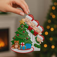 Load image into Gallery viewer, Christmas ornament with children around a tree, held by a hand with a blurred festive background.
