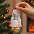 Load image into Gallery viewer, Personalized gender reveal Christmas ornament for baby girl featuring a pastel cake design with a cute elephant topper and its a gender message, soft pink and blue tones with layered cake details and glossy finish, styled as a sweet holiday keepsake for expecting parents, baby announcement and first Christmas memories, displayed on a warm wooden background with cozy Christmas lights, baby shoes and festive decor creating a joyful and heartwarming celebration scene
